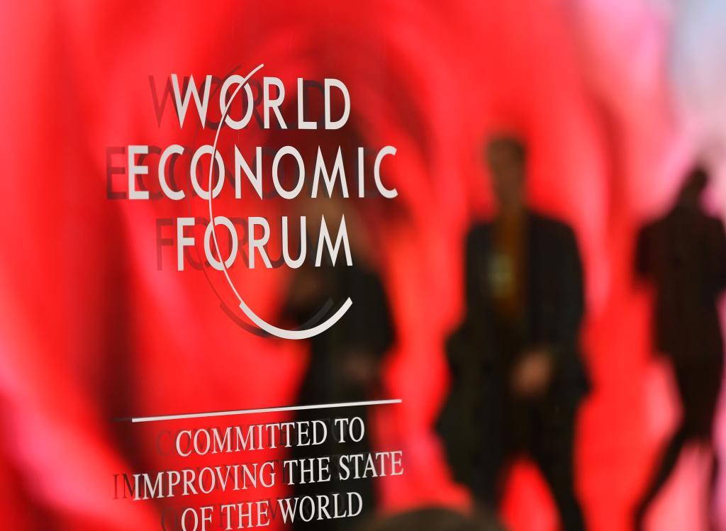 1月15日，在瑞士达沃斯，人们走过世界经济论坛标识。（图/新华社）